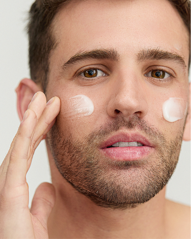 Close-up of a man applying dots of Inskin Co moisturiser to his cheeks with his fingertips.